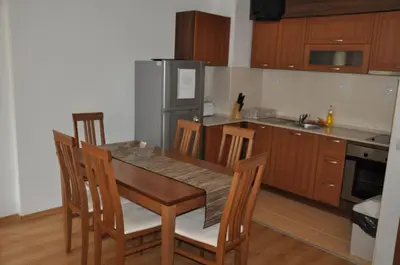 a kitchen with a table and chairs and a refrigerator at PM Services Semiramida Apartments in Borovets