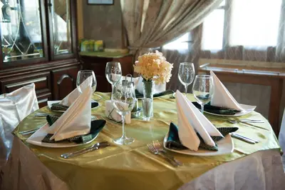 a table with a yellow table cloth with napkins and wine glasses at Globus Hotel in Plovdiv