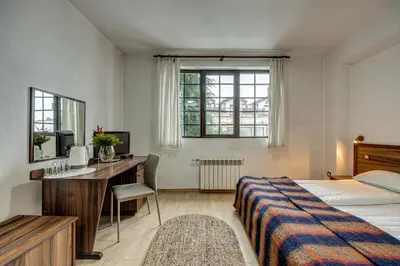 a bedroom with a bed and a desk with a computer at Ema Hotel Bansko in Bansko