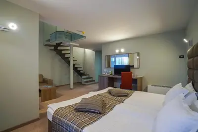 a bedroom with a bed with a staircase in the background at Perelik Hotel in Pamporovo