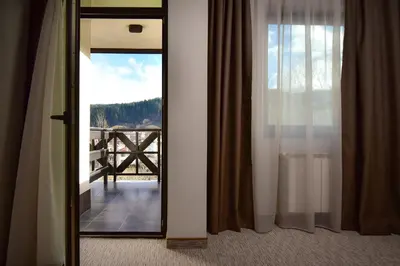 a door to a room with a view of a balcony at Rhodopi Home Hotel Chepelare- Half Board & Wellness in Chepelare