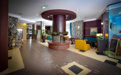 a lobby of a hotel with a fireplace in the middle at Rhodopi Home Hotel Chepelare- Half Board & Wellness in Chepelare