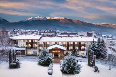 a hotel with snow covered mountains in the background at Four Points by Sheraton Bansko in Bansko
