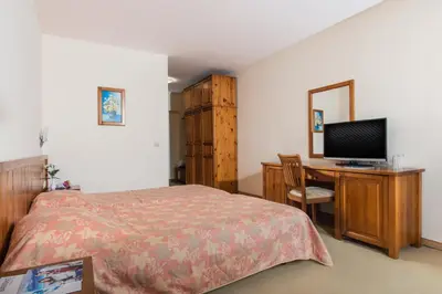 a bedroom with a bed and a desk with a television at Mura Hotel in Bansko