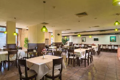 a dining room with tables and chairs and lights at Mura Hotel in Bansko