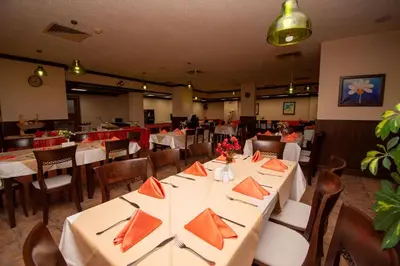 a restaurant with white tables and chairs with orange napkins at Mura Hotel in Bansko