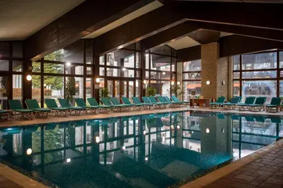 a swimming pool with chairs and a building at Hotel Pirin SKI & SPA in Bansko