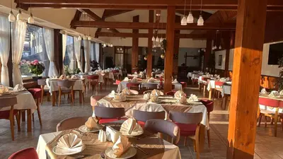 a restaurant with wooden tables and chairs and tablesearcher at Hotel Pirin SKI & SPA in Bansko