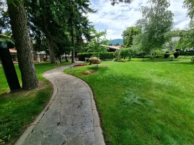 a stone path through a grassy yard with trees at Hotel Pirin SKI & SPA in Bansko