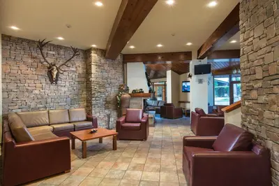 a lobby with leather furniture and a stone wall at Hotel Pirin SKI & SPA in Bansko