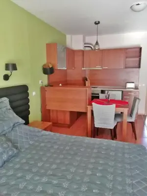 a bedroom with a bed and a kitchen with a table at Pirin Place Bansko in Bansko