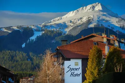 a hotel with a snow covered mountain in the background at MPM Hotel Sport Ski-in, Ski-out in Bansko