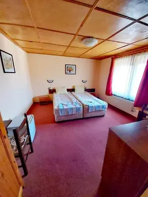 a large room with two beds and a table and windows at Family Hotel Santo Bansko in Bansko