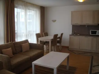 a living room with a couch and a table and a kitchen at Winslow Elegance Apartments in Bansko