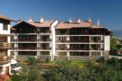 a large white apartment building with a roof at Winslow Elegance Apartments in Bansko