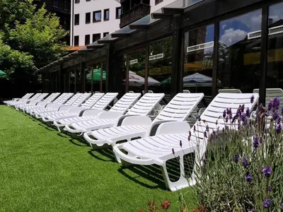 a row of white lawn chairs in front of a building at Hotel Casa Karina Bansko - Half Board & All Inclusive in Bansko