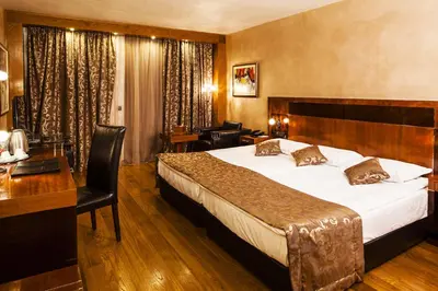 a hotel room with a large bed and a desk at Hotel Anel in Sofia