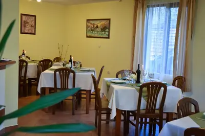 a dining room with white tables and chairs and a window at Lina Hotel in Bansko
