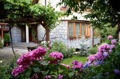 a garden with pink flowers in front of a house at Lina Hotel in Bansko
