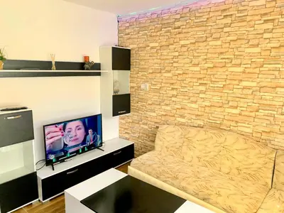a living room with a tv and a brick wall at Villa Eti in Dospat