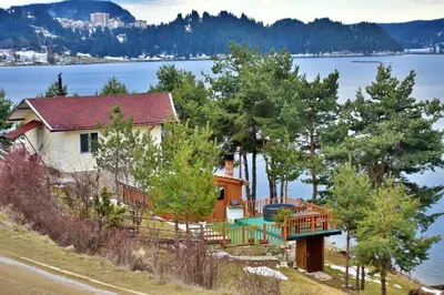 a house with a deck next to the water at Villa Eti in Dospat
