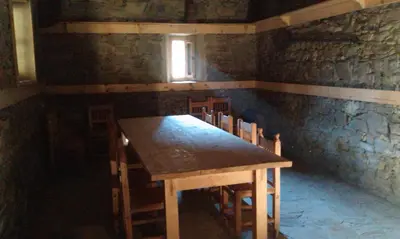 a wooden table and chairs in a room with a window at Кюповата къща 1860 Qpova house in Kovachevitsa