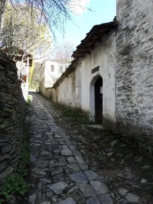 an old stone alley with a building and a street at Кюповата къща 1860 Qpova house in Kovachevitsa