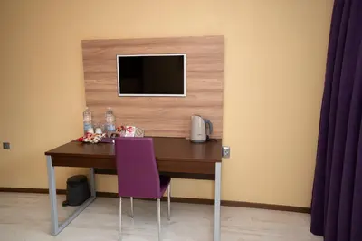 a desk with a purple chair and a tv on a wall at Guest house Traikovi in Petrich