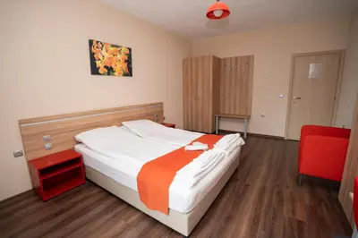 a bedroom with a bed and a red chair at Guest house Traikovi in Petrich