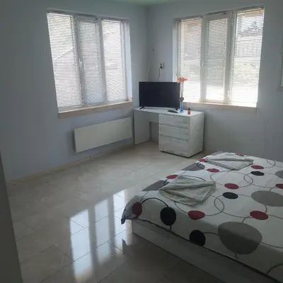 a bedroom with a bed and a desk and windows at Viktoria House in Sapareva Banya