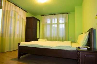 a bed in a green room with a window at Guest House Ivan in Cherni Osŭm