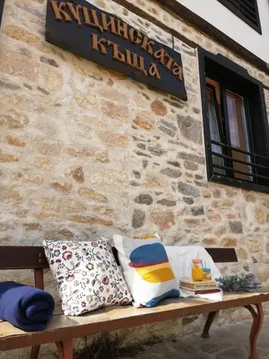 a bench sitting in front of a stone building with pillows at Kutsinska House in Progled