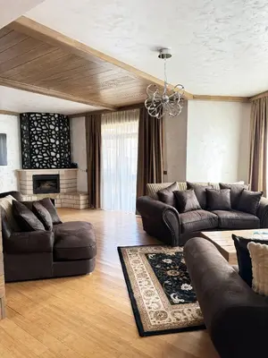 a living room with leather furniture and a chandelier at V Chalet Residence in Velingrad