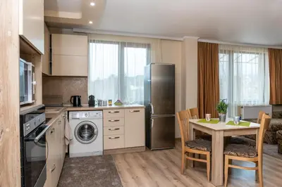 a kitchen with a table and a kitchen with a refrigerator at Panorama Apartment in Velingrad