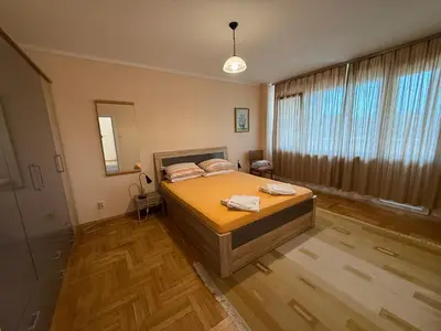 a bedroom with a bed and a large window at Apartment Durvenitza in Sofia
