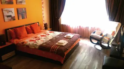 a bedroom with a bed and a chair and a window at Apartments Vasil Levski in Plovdiv
