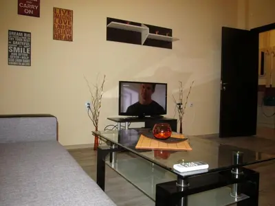 a living room with a glass table and a television at Apartments Vasil Levski in Plovdiv