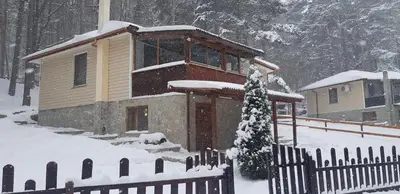 a small house in the snow with a fence at Villa Vanessa Koprivki Area in Tsar Kaloyan