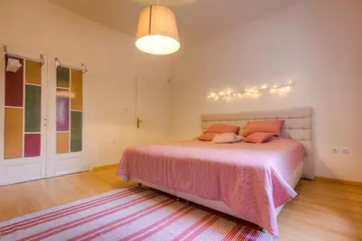 a bedroom with a bed with pink sheets and a rug at Guest house Maison 21 in Plovdiv