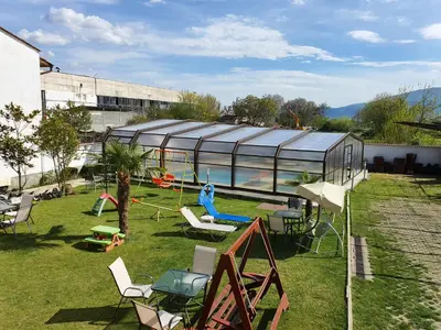 a garden with a glass house with a woman sitting on a swing at White House in Ognyanovo