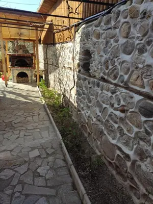 a stone wall in front of a building with a fireplace at Guesthouse Argacho in Stob