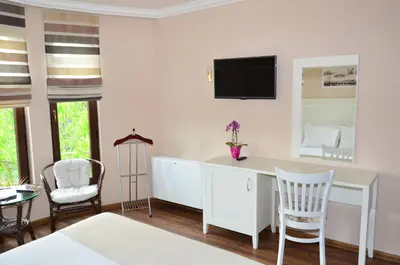 a room with a desk with chairs and a tv on the wall at Guesthouse Green Fields in Garmen