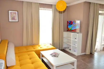 a living room with a yellow couch and a table at Guesthouse Green Fields in Garmen