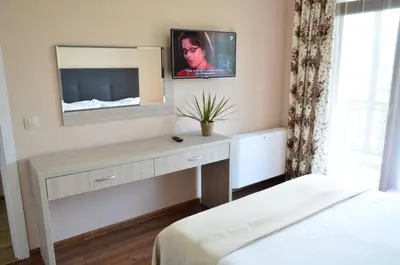 a bedroom with a desk with a tv on the wall at Guesthouse Green Fields in Garmen