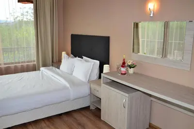 a hotel room with a bed and a counter with a window at Guesthouse Green Fields in Garmen