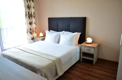 a bedroom with a large bed with white sheets and pillows at Guesthouse Green Fields in Garmen