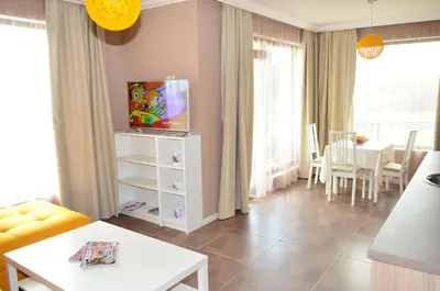 a living room with a tv and a table at Guesthouse Green Fields in Garmen