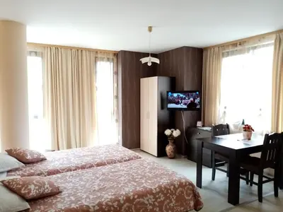 a bedroom with a bed and a table and a television at Apart Hotel Rosen in Sofia