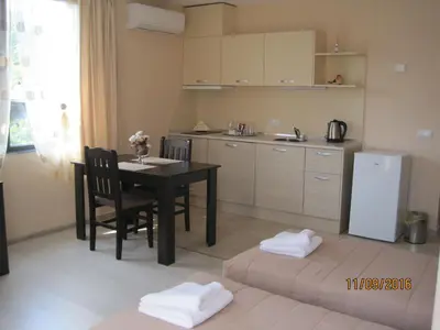 a kitchen with a table and chairs and a refrigerator at Apart Hotel Rosen in Sofia