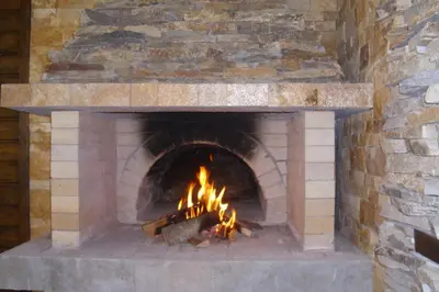 a brick oven with a fire in it at Ваканционна къща ,,Родопски уют 